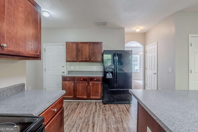 6285 Polar Fox Ct, Riverdale, GA 30296 - kitchen featuring black fridge, light wood-style flooring, a textured ceiling, arched walkways, and light countertops