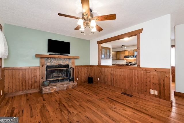 22 Ridge Haven Dr, Cleveland, GA 30528 - unfurnished living room with wainscoting, wooden walls, a fireplace, wood finished floors, and a ceiling fan