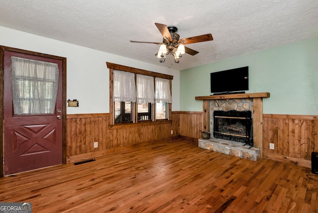 22 Ridge Haven Dr, Cleveland, GA 30528 - unfurnished living room featuring wainscoting, wood finished floors, a textured ceiling, a ceiling fan, and a fireplace
