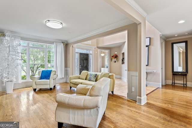 living room featuring light wood finished floors, crown molding, and baseboards