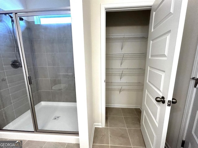 118 Garrett Dr, Eatonton, GA 31024 - full bathroom featuring tile patterned flooring, a shower stall, a walk in closet, and baseboards