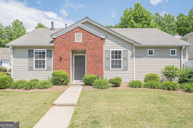 view of front of property with a front lawn, brick siding, and roof with shingles