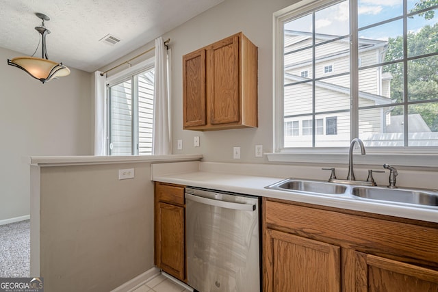 kitchen with stainless steel dishwasher, a sink, brown cabinetry, healthy amount of natural light, and a textured ceiling