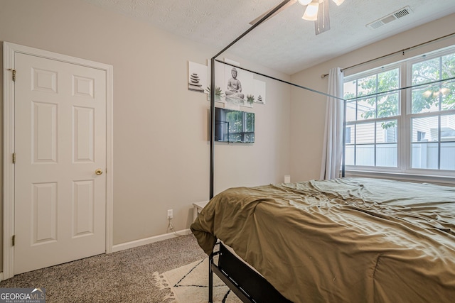 carpeted bedroom with a textured ceiling, baseboards, and a ceiling fan