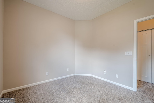 carpeted spare room featuring baseboards and a textured ceiling