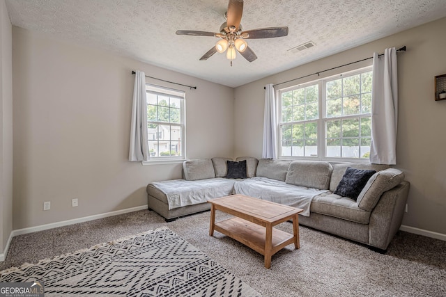 carpeted living area featuring a ceiling fan, baseboards, and a textured ceiling
