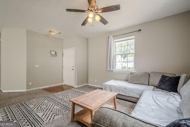 carpeted living room featuring baseboards, ceiling fan, and a textured ceiling