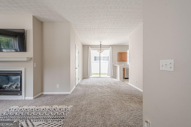 unfurnished living room featuring carpet floors, baseboards, a glass covered fireplace, and a textured ceiling