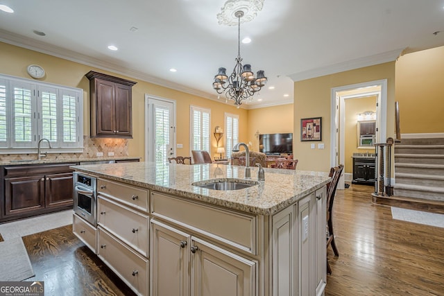 2295 Falmouth Ct SE Unit 23, Smyrna, GA 30080 - kitchen with crown molding, dark brown cabinetry, a center island with sink, plenty of natural light, and a breakfast bar