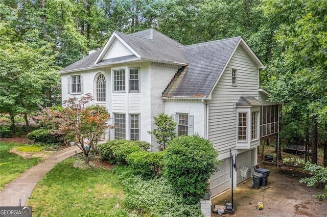 1763 Benningfield Dr SW, Marietta, GA 30064 - view of front facade with a garage, a shingled roof, view of scattered trees, brick siding, and a sunroom