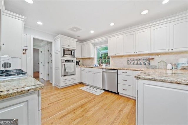 1763 Benningfield Dr SW, Marietta, GA 30064 - kitchen featuring appliances with stainless steel finishes, white cabinets, light wood-style flooring, light stone countertops, and recessed lighting