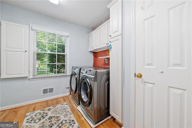 1763 Benningfield Dr SW, Marietta, GA 30064 - washroom featuring washing machine and dryer, cabinet space, light wood-style flooring, baseboards, and a textured ceiling
