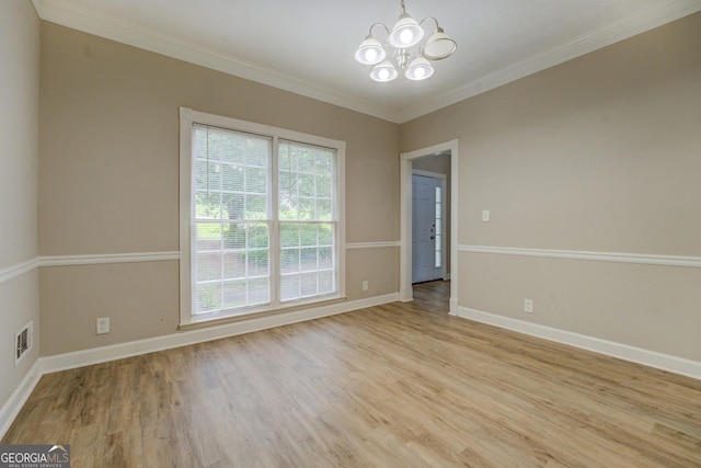 empty room with a chandelier, light wood-style floors, baseboards, and crown molding