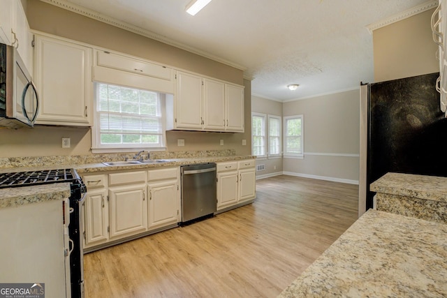 kitchen featuring stainless steel appliances, crown molding, light wood-style floors, light countertops, and a sink