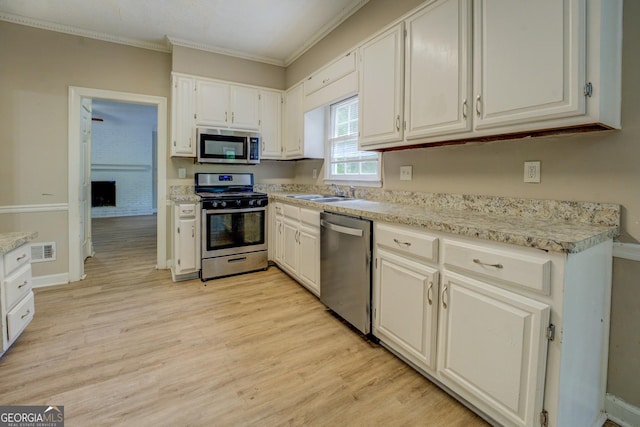 kitchen with stainless steel appliances, crown molding, light wood-style flooring, white cabinetry, and a sink