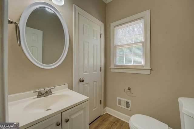 bathroom with toilet, wood finished floors, vanity, and baseboards