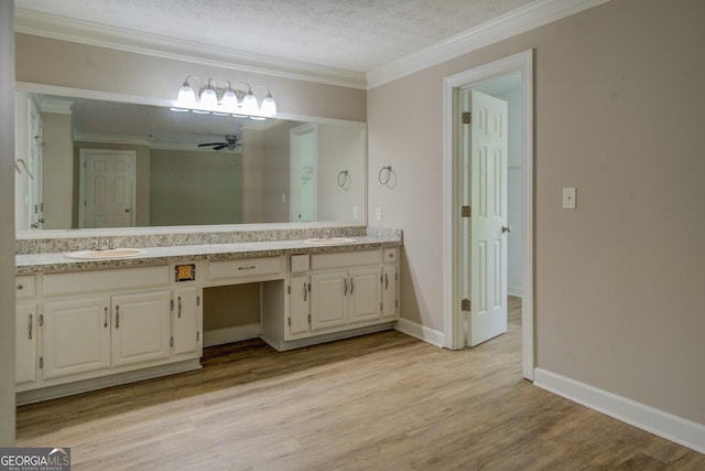 bathroom featuring ornamental molding, wood finished floors, double vanity, a ceiling fan, and baseboards