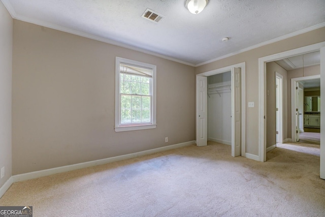 unfurnished bedroom featuring attic access, carpet flooring, crown molding, a closet, and baseboards