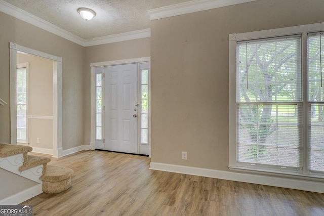 foyer with plenty of natural light, light wood finished floors, stairway, crown molding, and a textured ceiling