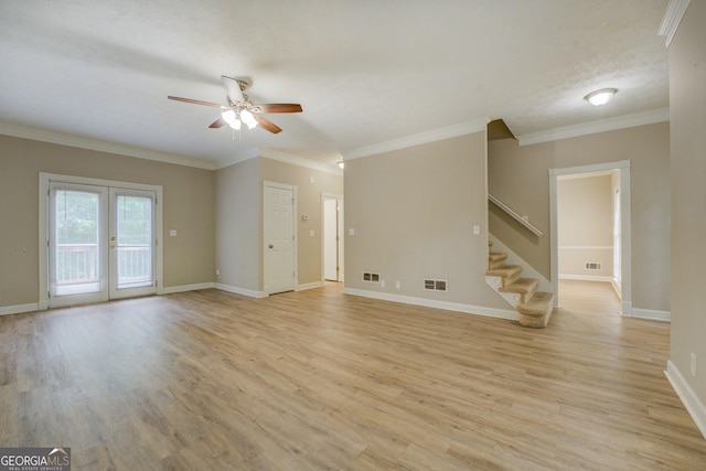 unfurnished living room featuring a ceiling fan, french doors, stairs, light wood-style floors, and crown molding