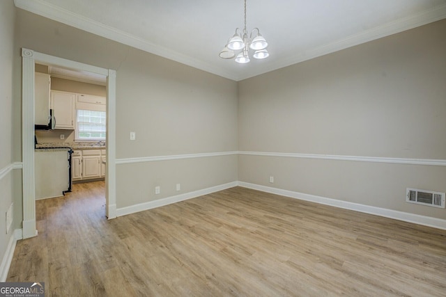 unfurnished room featuring ornamental molding, light wood-style flooring, a chandelier, and baseboards