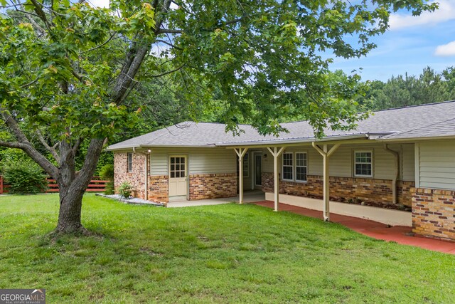 back of property featuring brick siding, a yard, a shingled roof, and a patio area