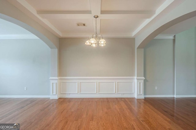 unfurnished room featuring wood finished floors, beamed ceiling, coffered ceiling, arched walkways, and a chandelier