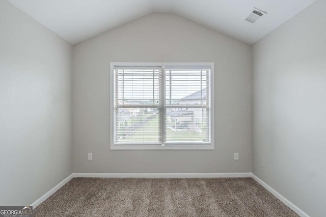 empty room featuring carpet floors, vaulted ceiling, and baseboards