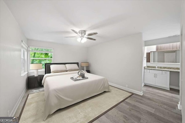 bedroom with baseboards, a sink, light wood-style flooring, and ceiling fan