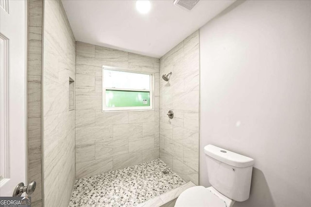 full bathroom featuring toilet and tiled shower