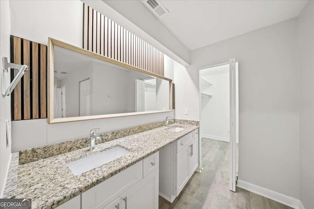 bathroom featuring wood finished floors, double vanity, and baseboards