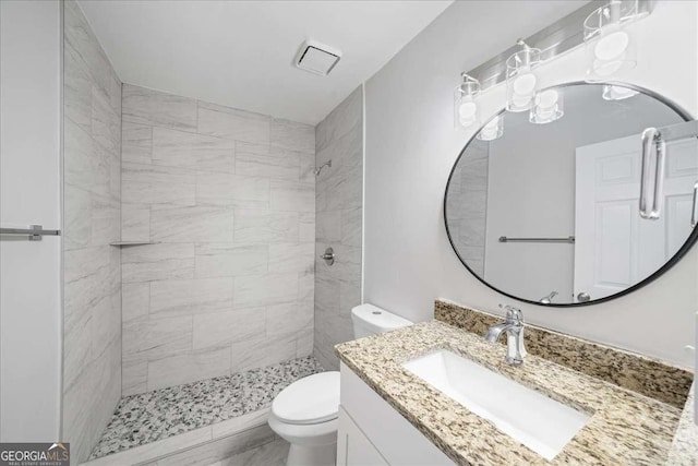full bathroom featuring toilet, tiled shower, and vanity