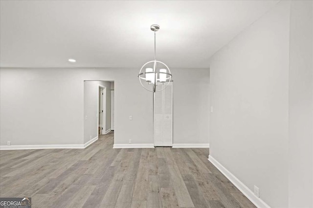 unfurnished dining area with a chandelier, wood finished floors, baseboards, and recessed lighting