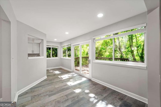 unfurnished sunroom with baseboards, recessed lighting, and wood finished floors