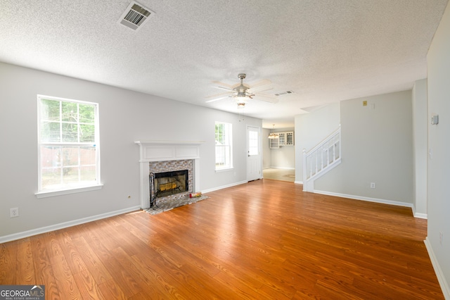 unfurnished living room with wood finished floors, healthy amount of natural light, a textured ceiling, stairs, and ceiling fan