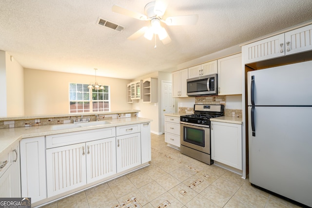 kitchen featuring appliances with stainless steel finishes, decorative backsplash, a ceiling fan, a sink, and a textured ceiling