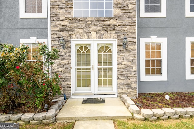 doorway to property with stone siding and stucco siding