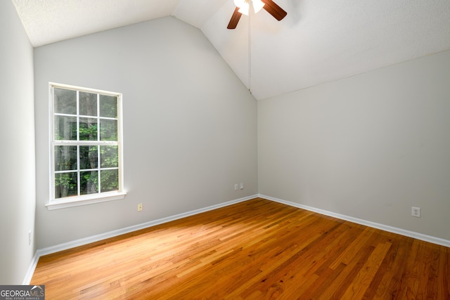 empty room with vaulted ceiling, a ceiling fan, wood finished floors, and baseboards