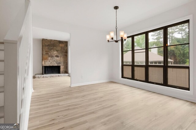 683 Highland Ct, Marietta, GA 30068 - unfurnished dining area with wood finished floors, a chandelier, baseboards, and a stone fireplace