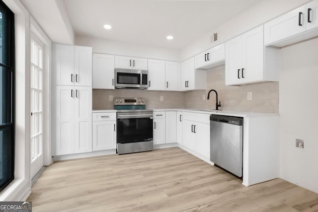 683 Highland Ct, Marietta, GA 30068 - kitchen featuring appliances with stainless steel finishes, a sink, light countertops, backsplash, and white cabinets