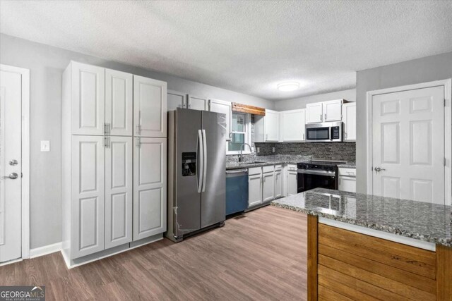 191 Nectar Pl, Dallas, GA 30132 - kitchen with appliances with stainless steel finishes, a sink, dark wood-type flooring, white cabinetry, and dark stone countertops