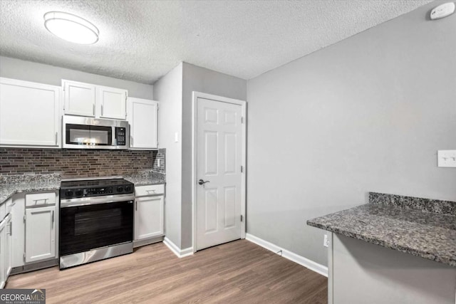 191 Nectar Pl, Dallas, GA 30132 - kitchen featuring stainless steel microwave, range with electric cooktop, light wood-type flooring, a textured ceiling, and white cabinetry