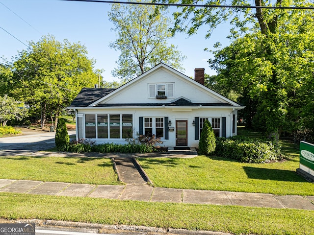 bungalow featuring a chimney and a front yard
