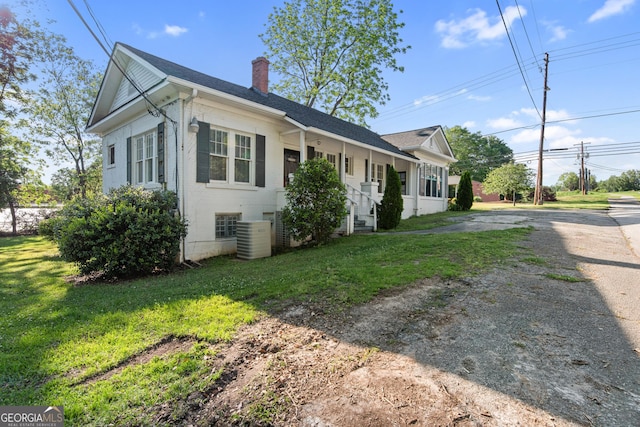 view of side of home featuring a chimney, a yard, and dirt driveway