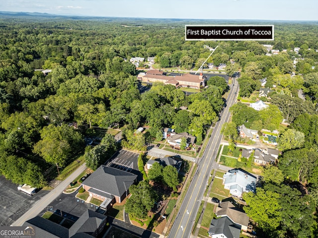 aerial view of property and surrounding area with a heavily wooded area and nearby suburban area