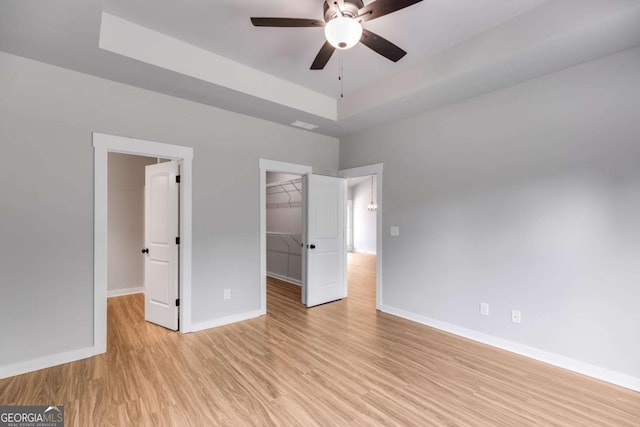 0 Grogan Rd, Buchanan, GA 30113 - unfurnished bedroom with a walk in closet, a tray ceiling, baseboards, light wood finished floors, and a closet