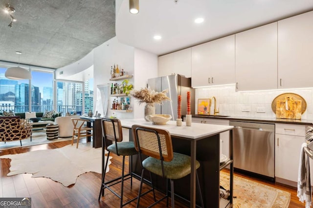 860 Peachtree St NE Unit 1513, Atlanta, GA 30308 - kitchen with appliances with stainless steel finishes, a sink, light wood-style floors, backsplash, and a wall of windows