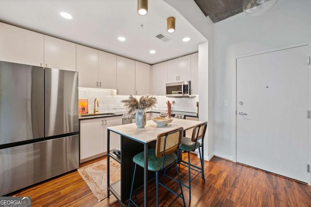 860 Peachtree St NE Unit 1513, Atlanta, GA 30308 - kitchen featuring stainless steel appliances, dark wood-type flooring, decorative backsplash, white cabinetry, and recessed lighting