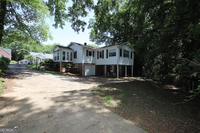 view of front of house with driveway, an attached garage, and a chimney