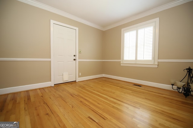 empty room featuring light wood-type flooring, baseboards, and crown molding